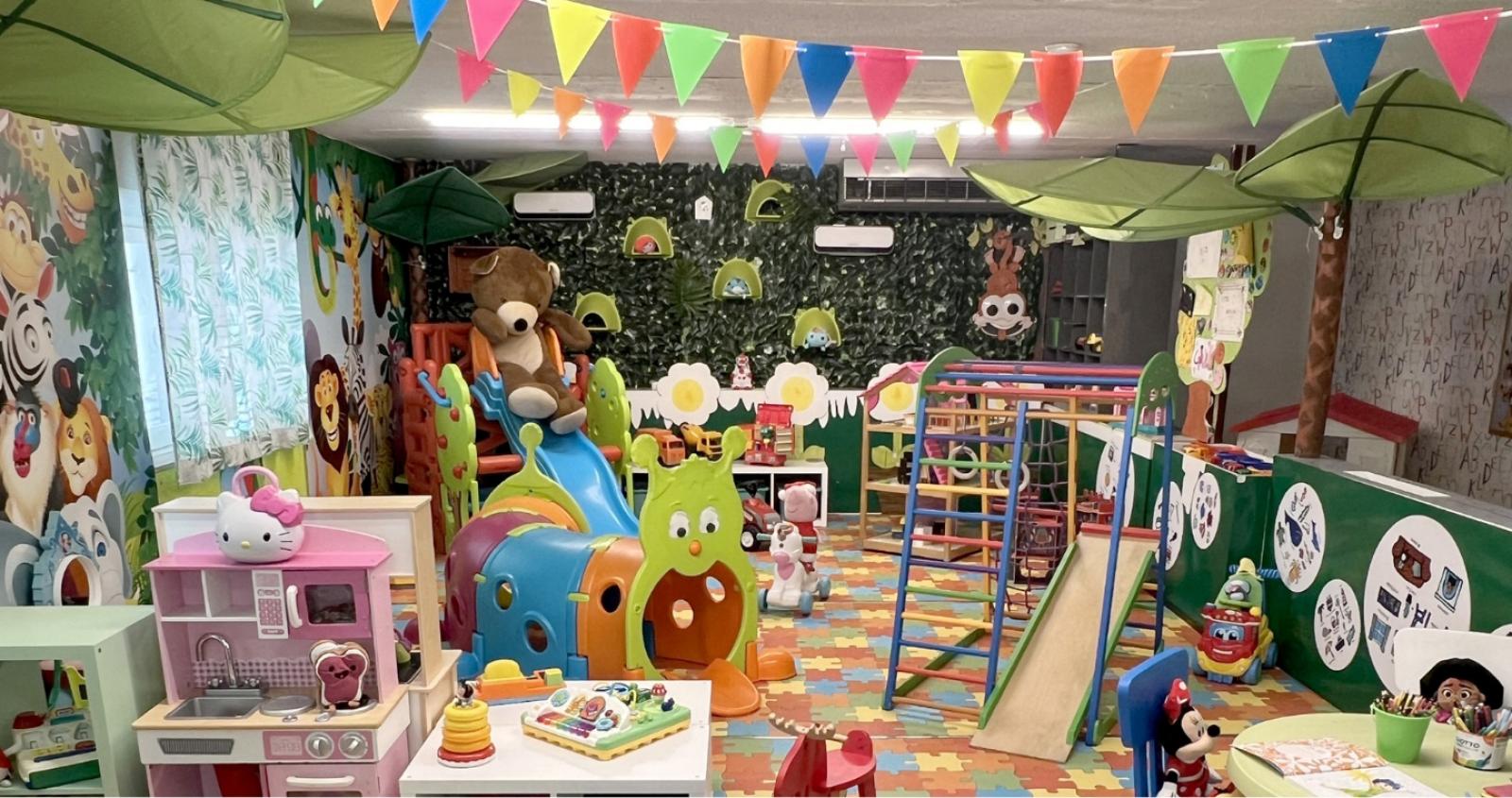 Area giochi colorata con scivoli, decorazioni di animali e giochi educativi.