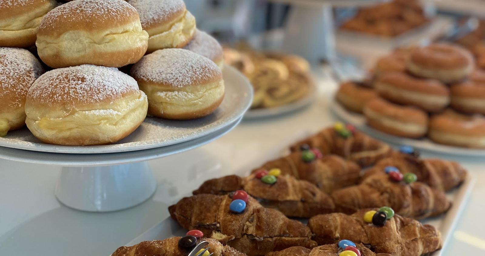 Vassoio di dolci assortiti con croissant e bomboloni spolverati di zucchero a velo.