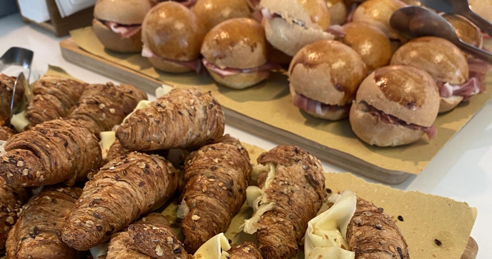 Cornetti integrali al formaggio e panini al prosciutto su un tavolo.