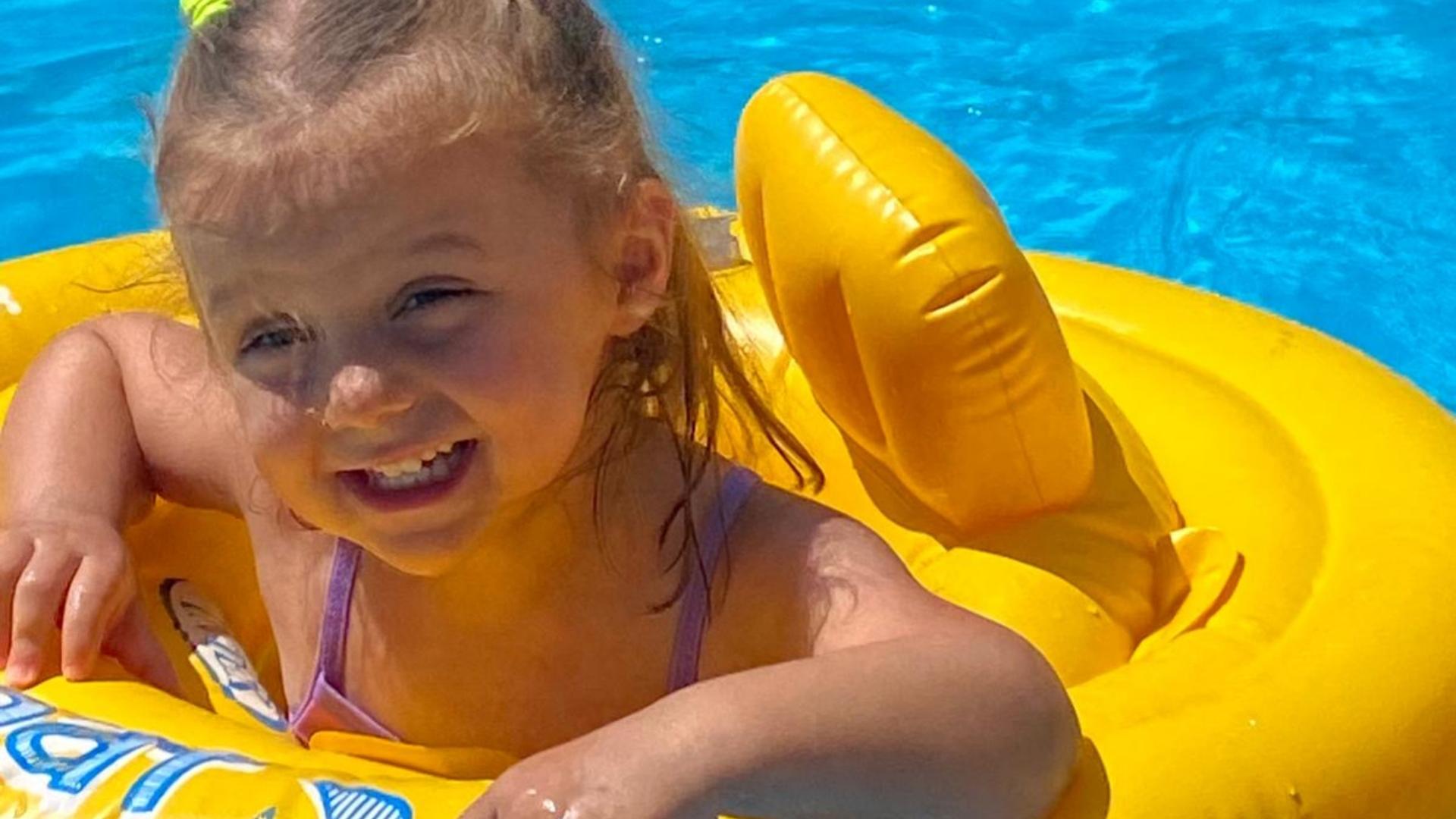 Bambina felice su un gonfiabile giallo in piscina.