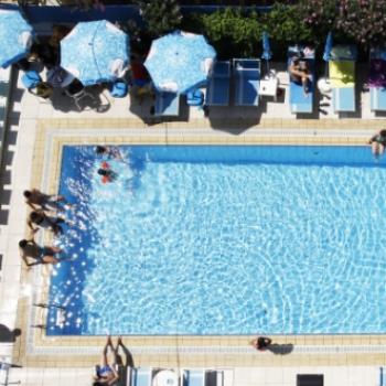 Vista dall'alto di una piscina con persone e ombrelloni.