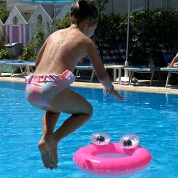 Persone saltano in piscina sotto un ombrellone Motta, giornata di divertimento estivo.